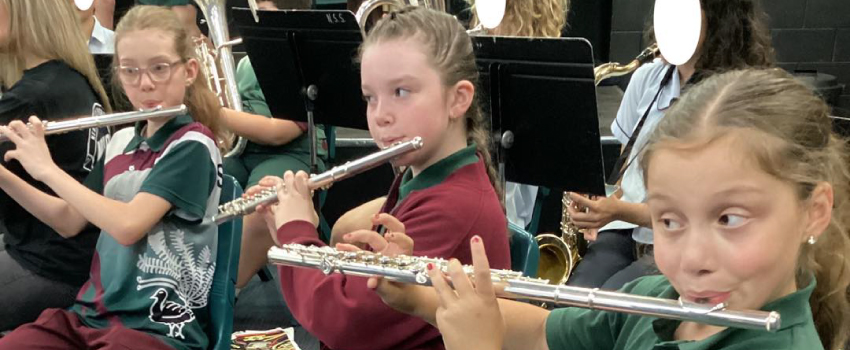 three students playing flute in band